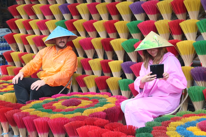 Khách quốc tế mặc áo mưa chụp ảnh selfie ở làng hương Thủy Xuân