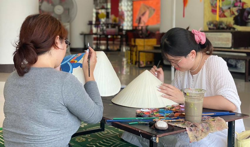 Khách vẽ tranh trên nón tại Không gian trưng bày, giới thiệu và trình diễn nghề truyền thống Huế