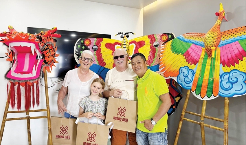 Distinguished Artisan Nguyen Dang Hoang (far right) with a foreign family experiencing kite-making