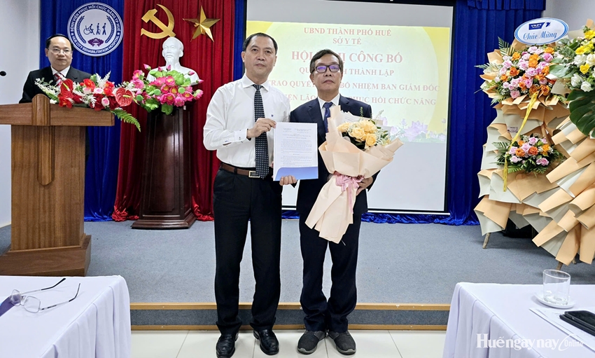 PGS.TS Trần Kiêm Hảo, Giám đốc Sở Y tế thành phố (bìa trái) trao quyết định và tặng hoa chúc mừng ông Nguyễn Khoa Nguyên được bổ nhiệm Giám đốc Bệnh viện Lão khoa - PHCN TP. Huế.  